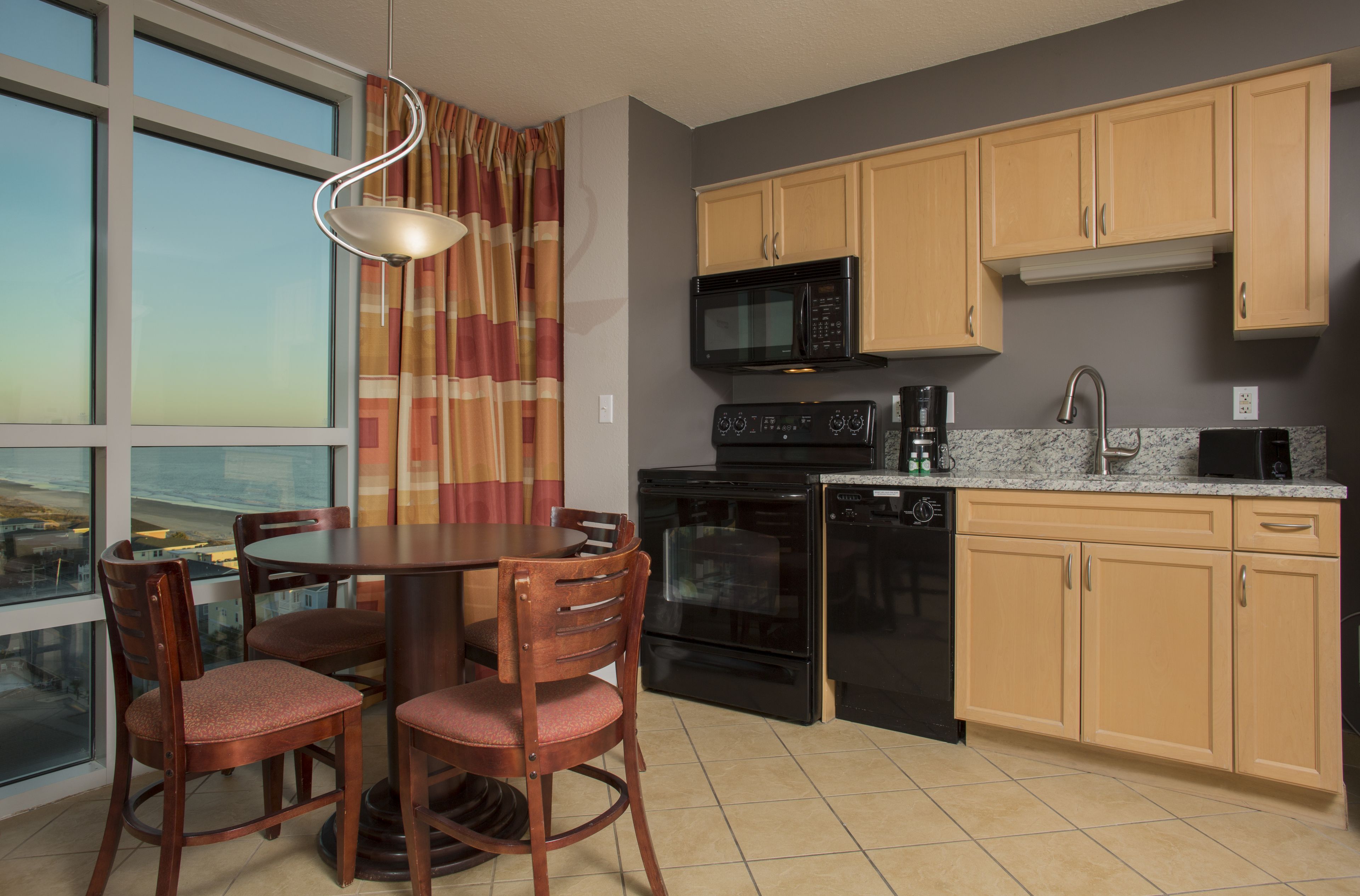 A kitchen with a dining table, chairs, a microwave, oven, and cabinets.
