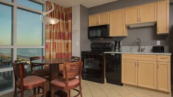 A kitchen with a dining table, chairs, a microwave, oven, and cabinets.