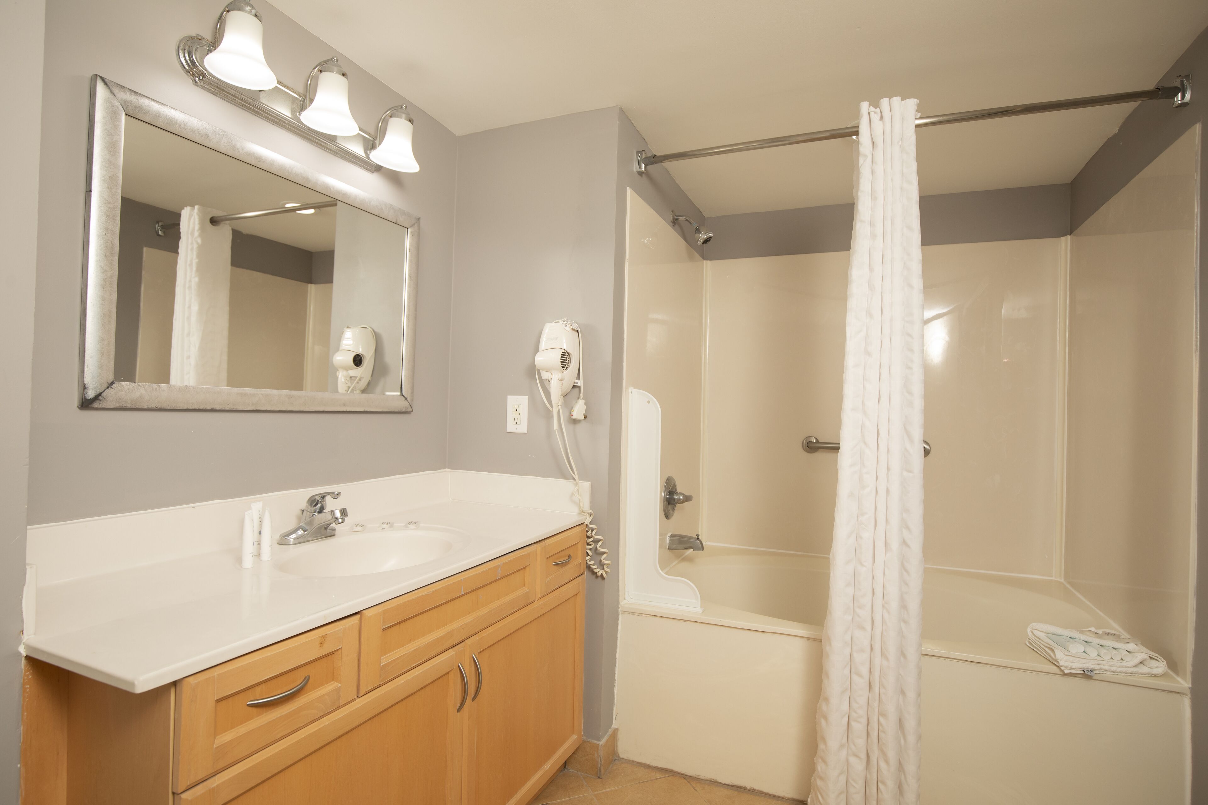 A bathroom with a sink, mirror, and shower.