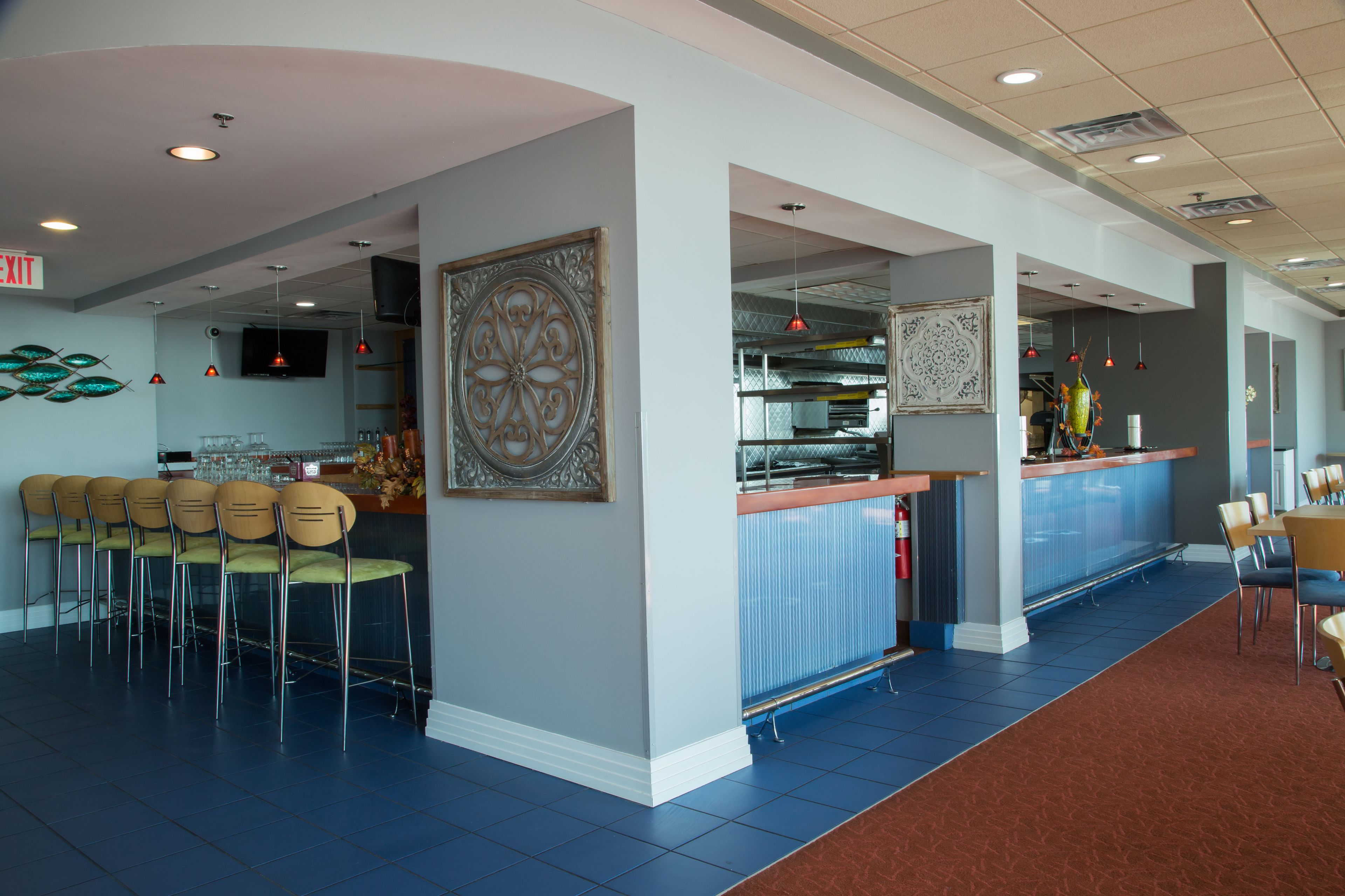A restaurant with a bar area, multiple chairs, and a large decorative wall piece.