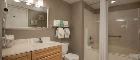 A bathroom with a sink, mirror, toilet, and shower.