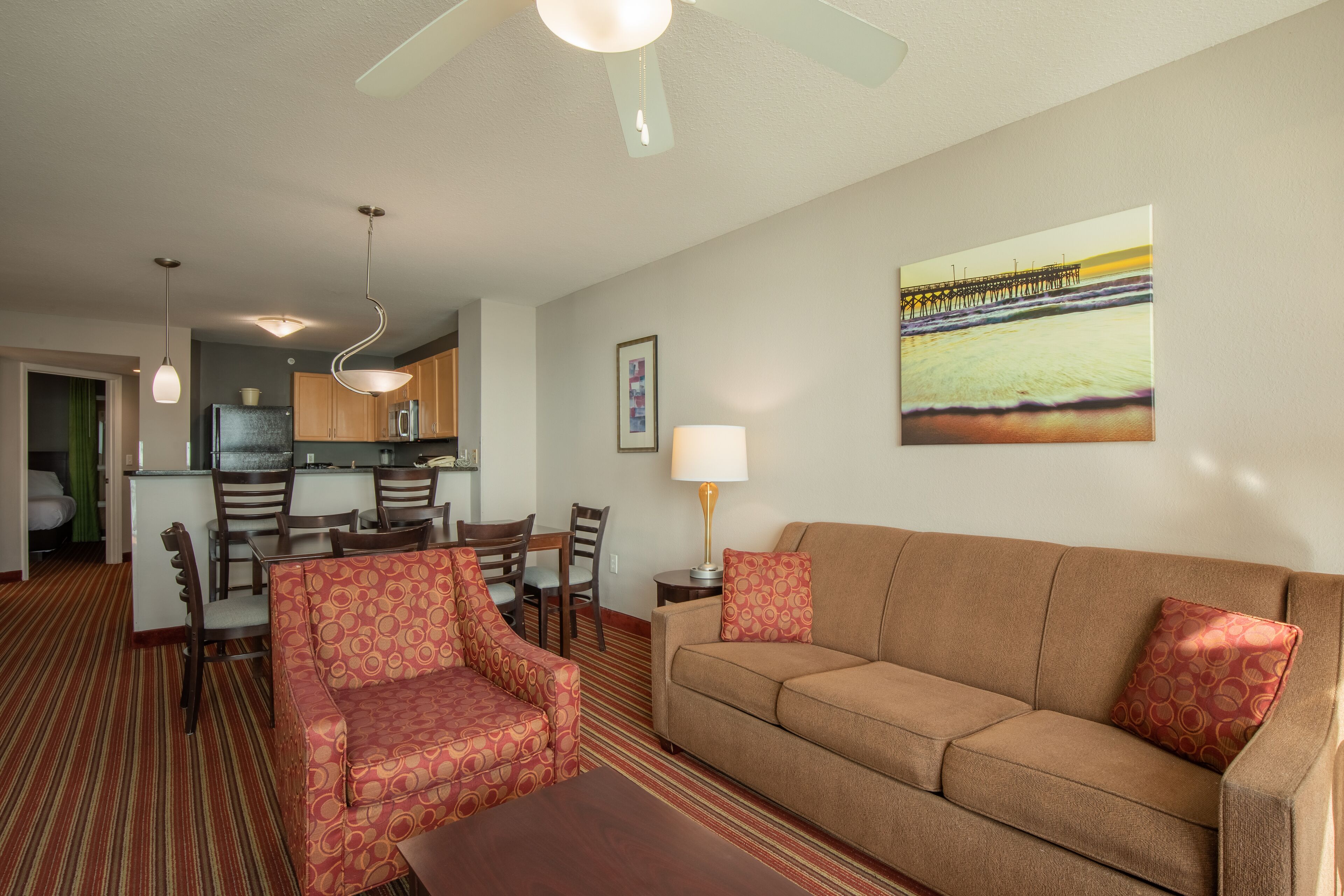 A hotel room with a living area, kitchenette, and a dining area.