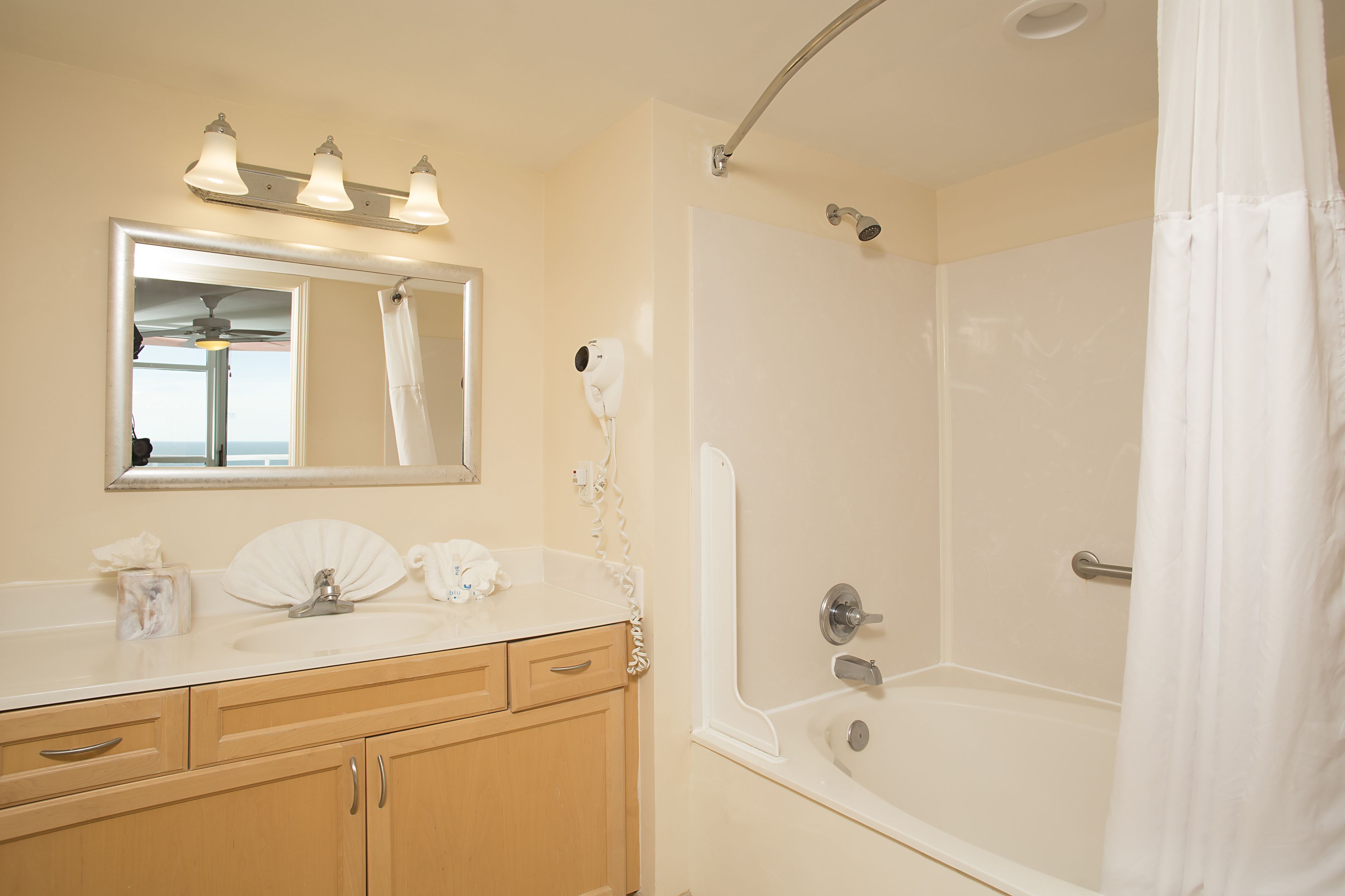 A bathroom with a sink, vanity, mirror, and shower.