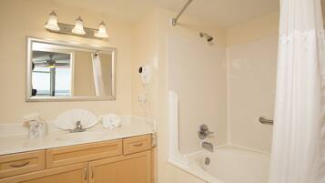 A bathroom with a sink, vanity, mirror, and shower.