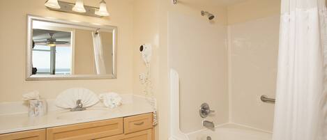 A bathroom with a sink, vanity, mirror, and shower.