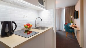 Een moderne keuken met witte metrotegels, een roestvrijstalen spoelbak, een zwarte waterkoker en een fruitschaal.