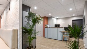 Een moderne receptie met een witte bakstenen muur, houten vloer en een zithoek met een bank.