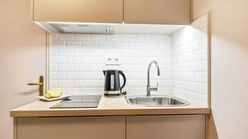 Een kleine keuken met een spoelbak, een waterkoker en een bord eten.