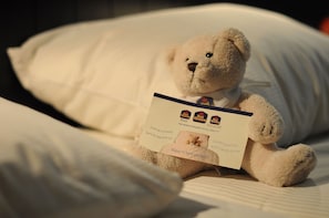 A teddy bear sitting on a bed with a card.