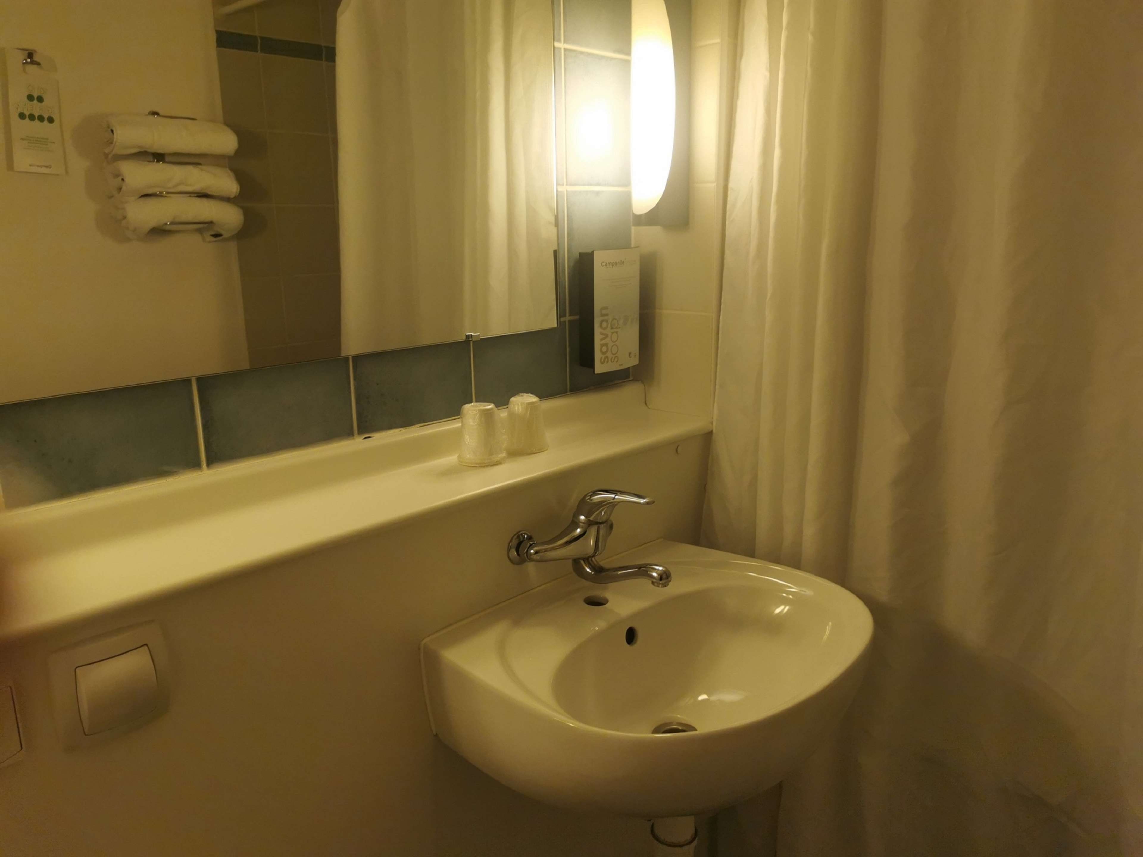 Un bany amb un lavabo, un mirall, un penjador de tovalloles i un dosificador de sabó.