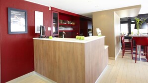 A modern kitchen with a wooden island, red walls, and a dining area with red chairs. - Campanile Manosque (Manosque)