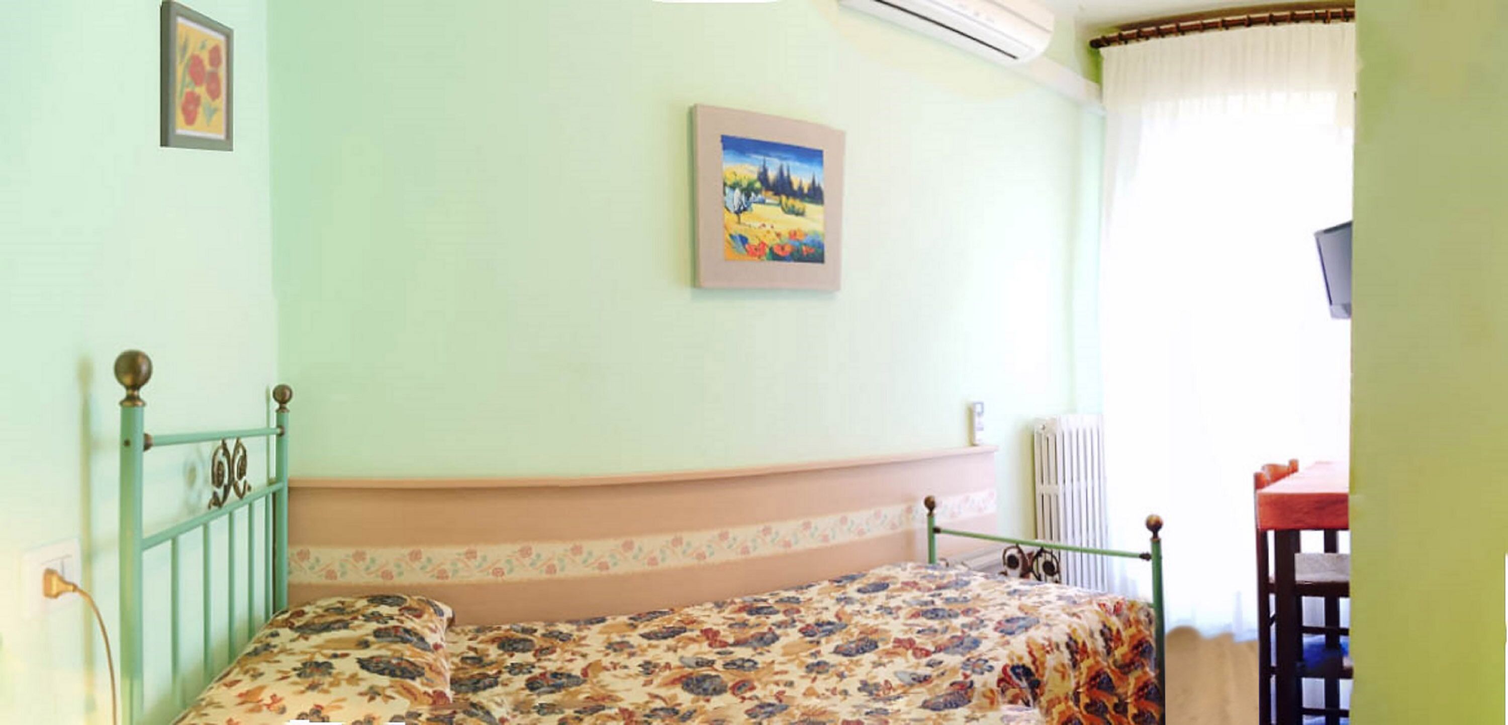 Un dormitorio con cama, un cuadro en la pared y un radiador.