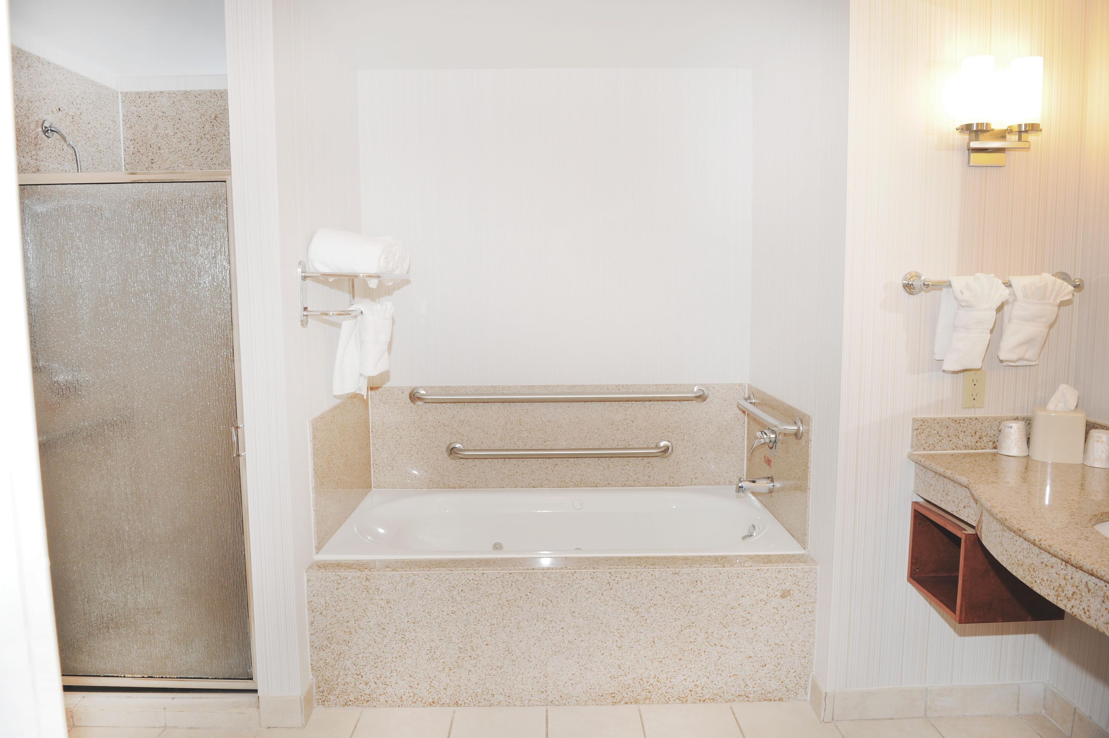 A bathroom with a bathtub, a shower, and a vanity with a mirror.