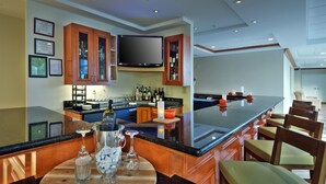 Une cuisine moderne dotée d’un grand îlot central, de meubles en bois et d’un téléviseur à écran plat fixé au-dessus de l’îlot.