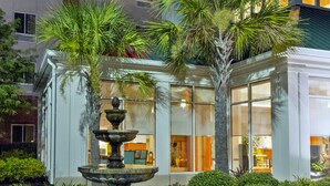 Un hôtel Hilton Garden Inn doté d’une fontaine et d’un aménagement paysager bien entretenu.
