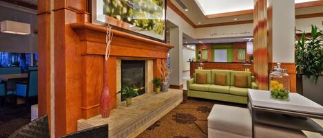 A lobby with a fireplace, a sofa, a coffee table, and a reception desk.