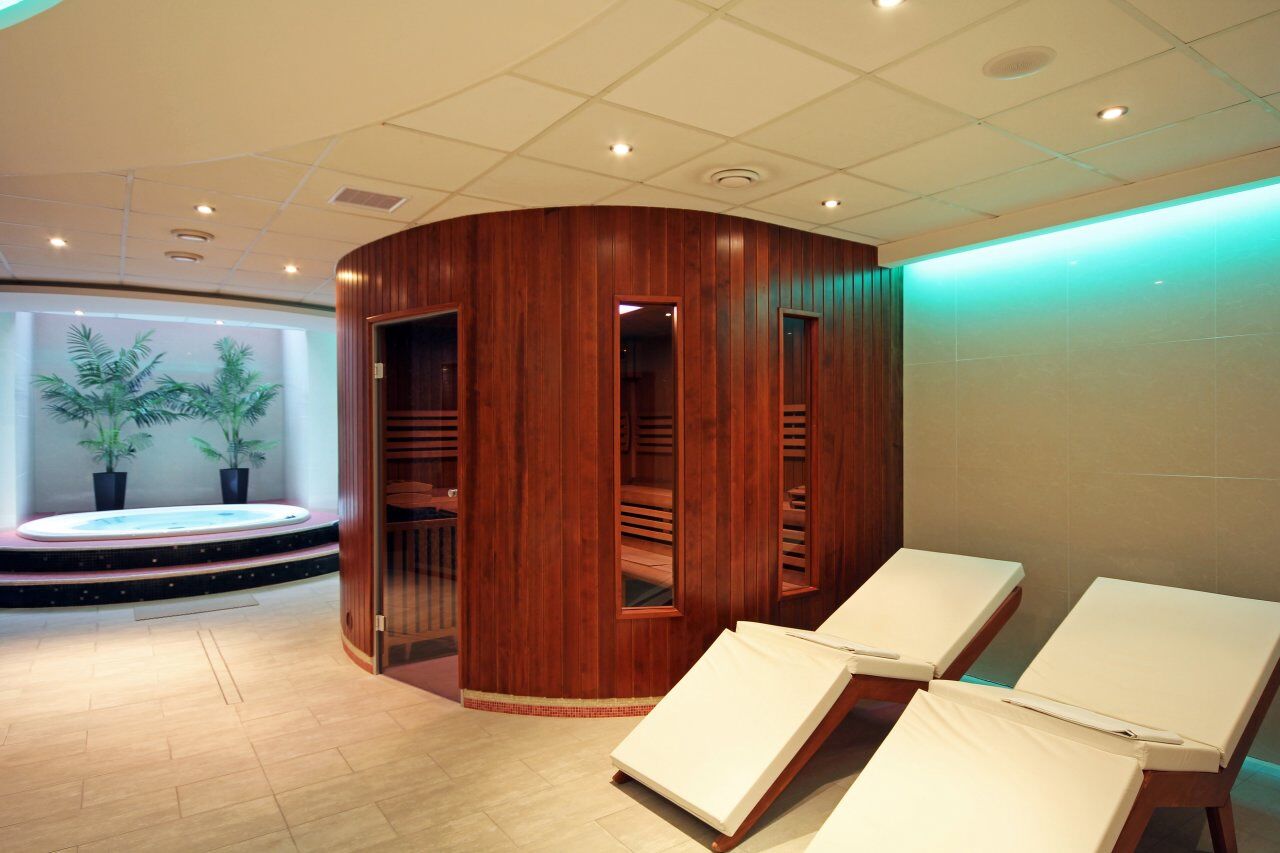 A spa room with wooden paneling, a hot tub, and two lounge chairs.