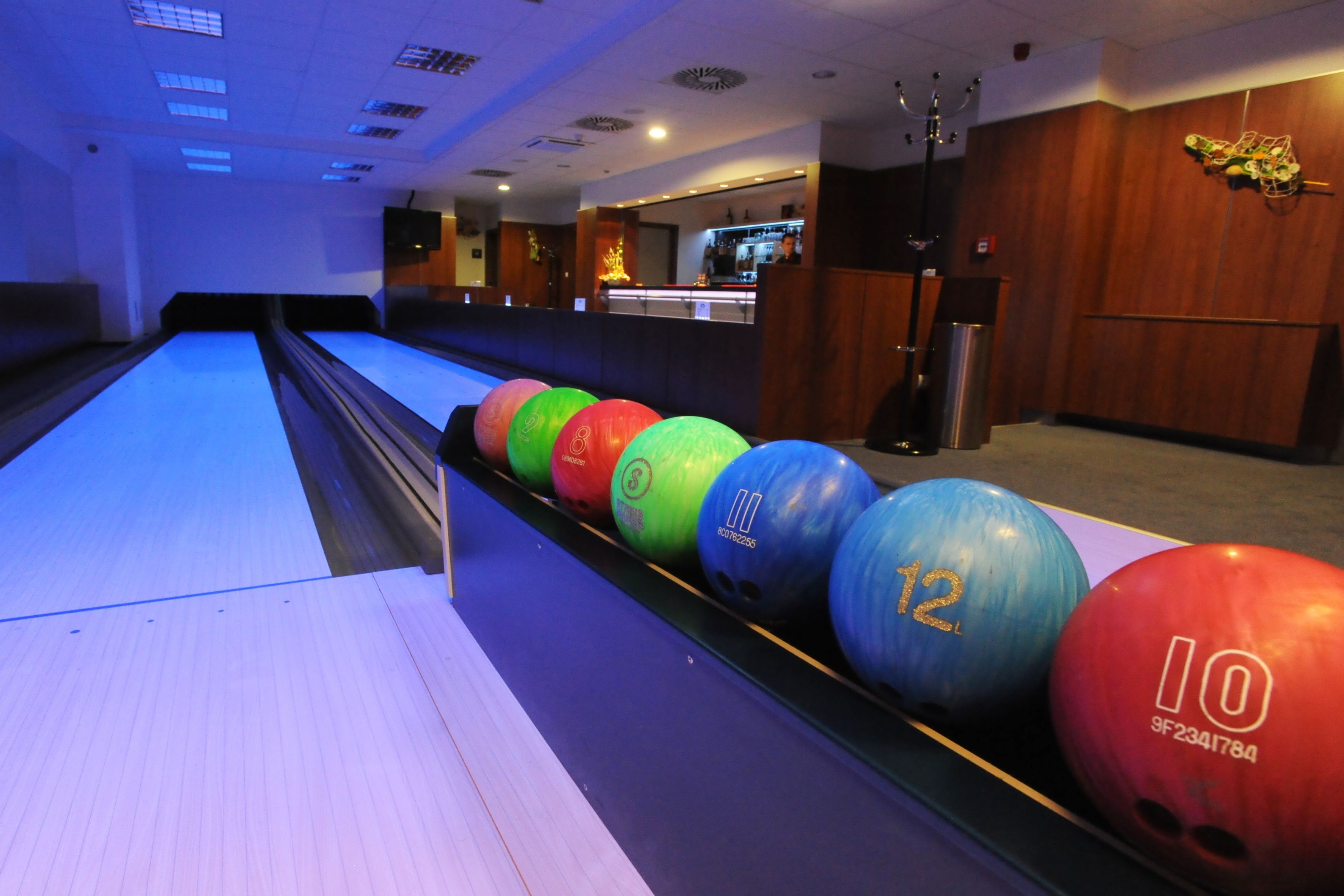A bowling alley with a row of colorful pins and a wooden floor.