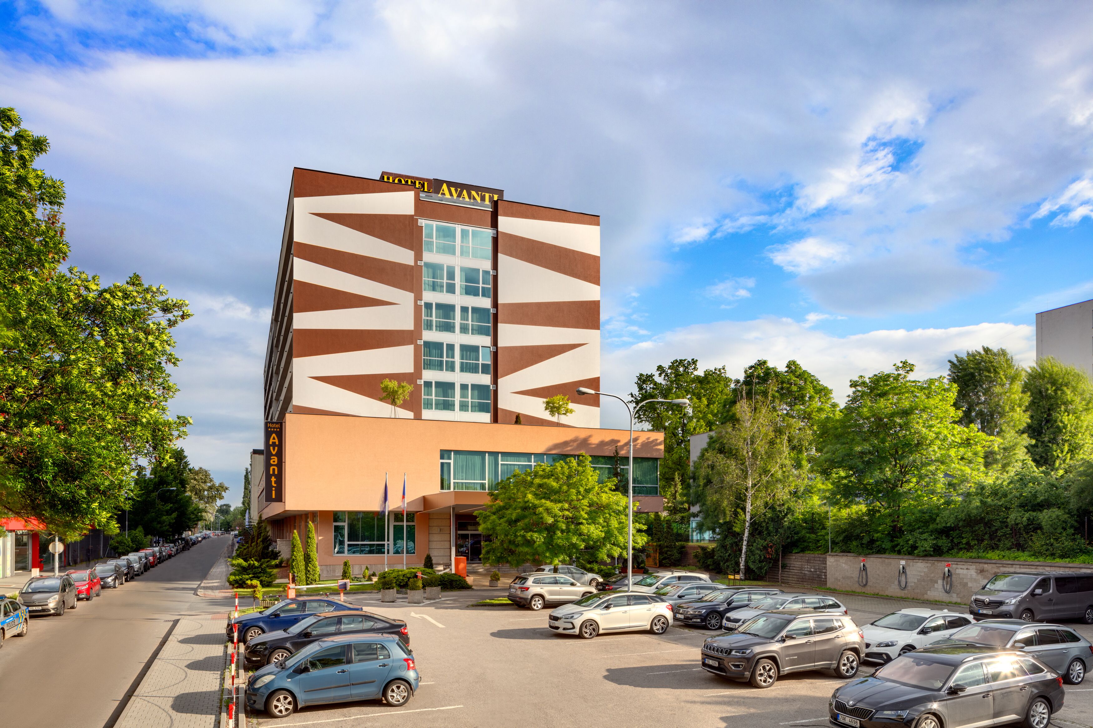 Hotel amb un disseny modern, amb façana geomètrica i un pàrquing ple de cotxes.