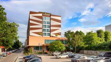 A hotel with a modern design, featuring a geometric facade and a parking lot with multiple cars.