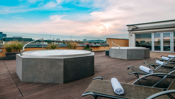 A rooftop terrace with a hot tub, lounge chairs, and a view of the city skyline. - Avanti Hotel Brno (Brno)