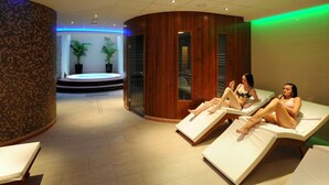 A spa area with two reclining chairs, a tiled floor, and a small pool area in the background. - Avanti Hotel Brno (Brno)