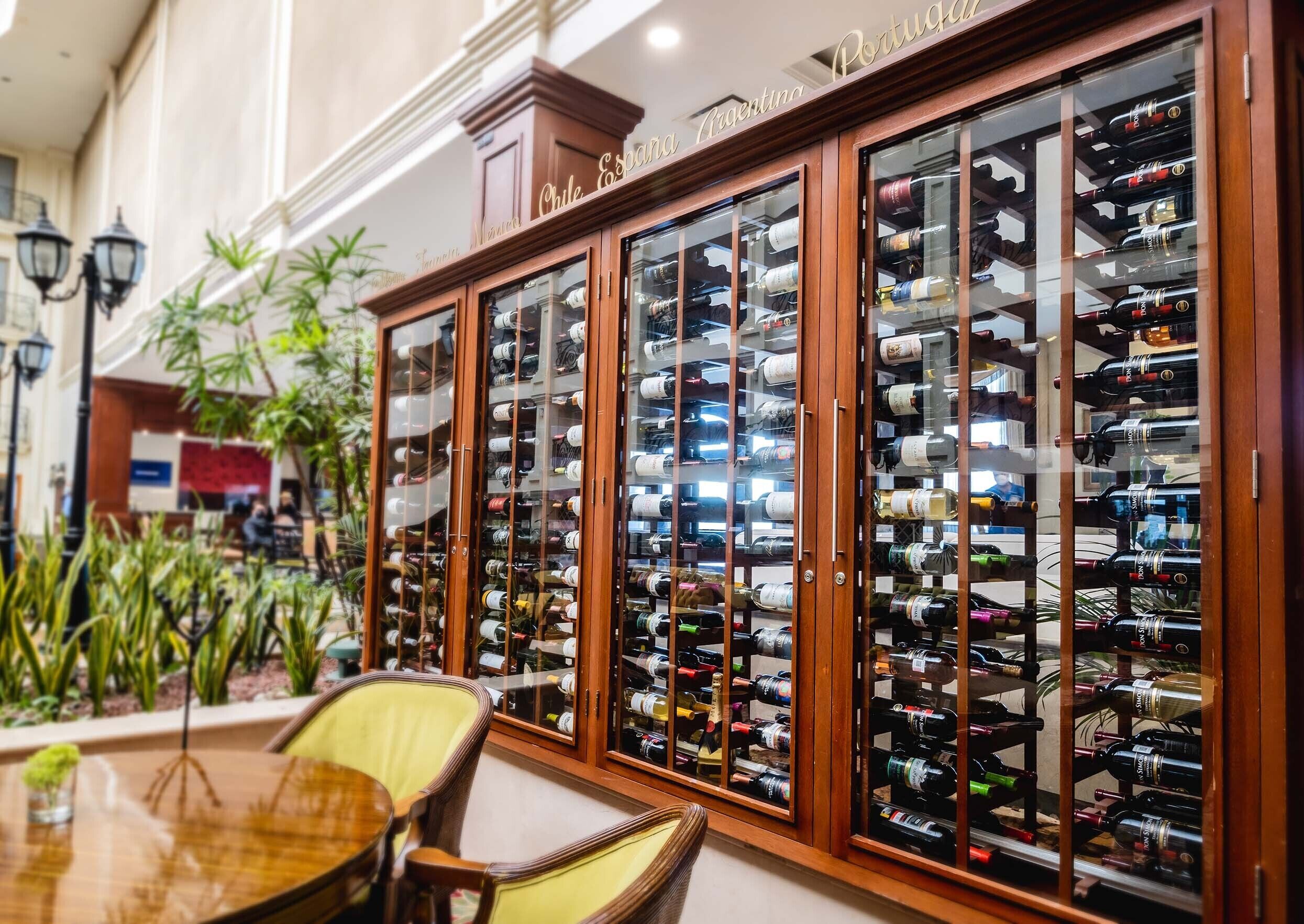 A wine cellar with wooden cabinets and glass doors, containing various bottles of wine.