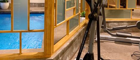A gym with exercise equipment and a pool area.