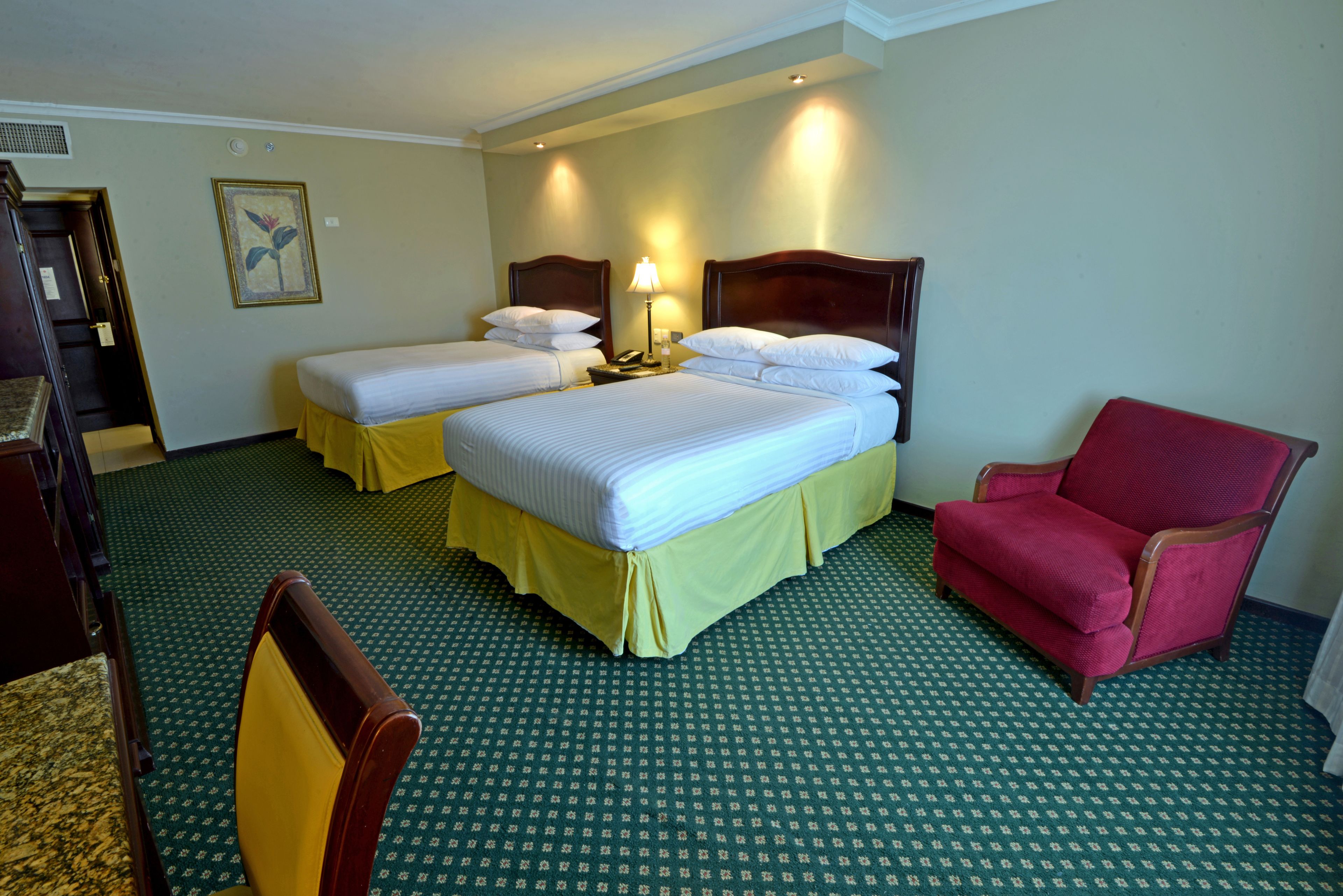 Habitación de hotel con dos camas, una silla y un escritorio.