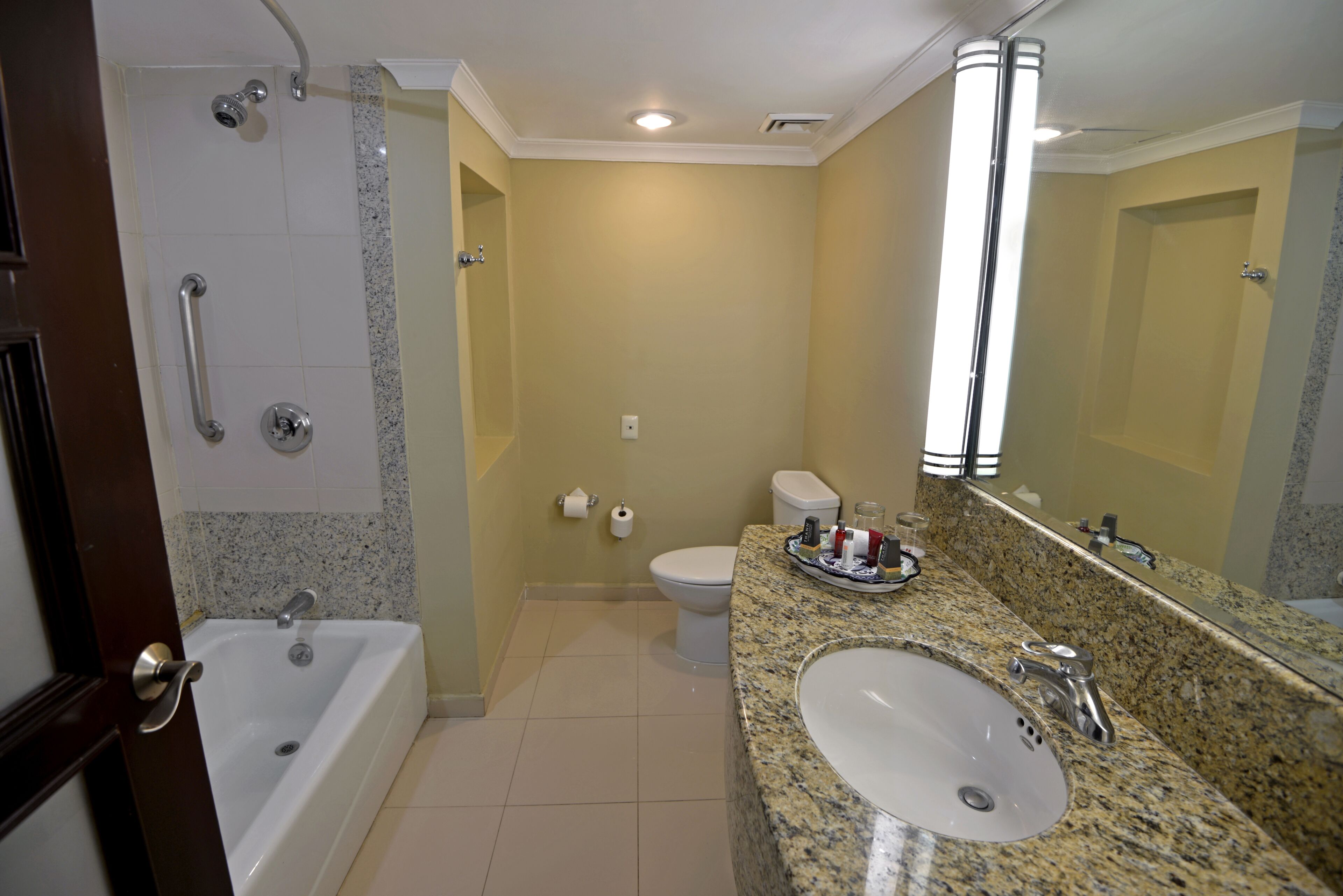 A bathroom with a bathtub, toilet, sink, and a large mirror.