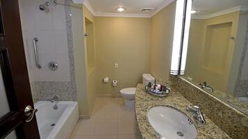 A bathroom with a bathtub, toilet, sink, and a large mirror.