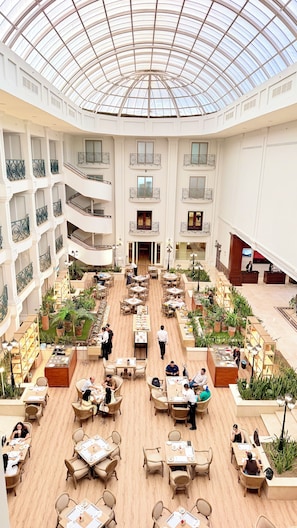 A spacious atrium with multiple dining areas, a central open space, and a glass ceiling. - Marriott Torreon (Torreón)