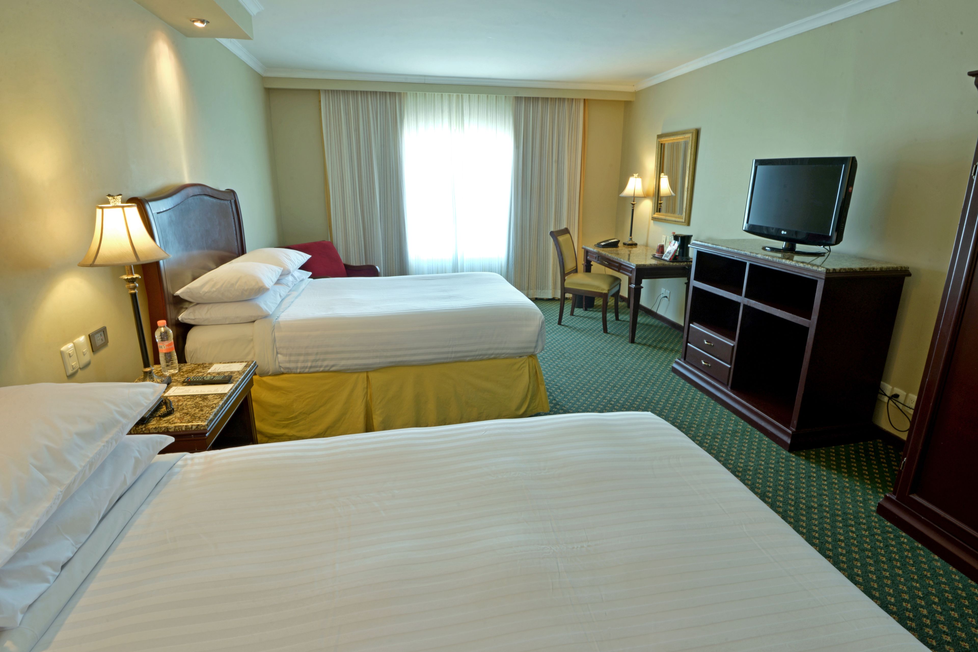 Una habitación de hotel con dos camas, un escritorio, un televisor y una silla.