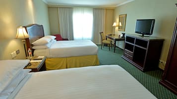 Una habitación de hotel con dos camas, un escritorio, un televisor y una silla.