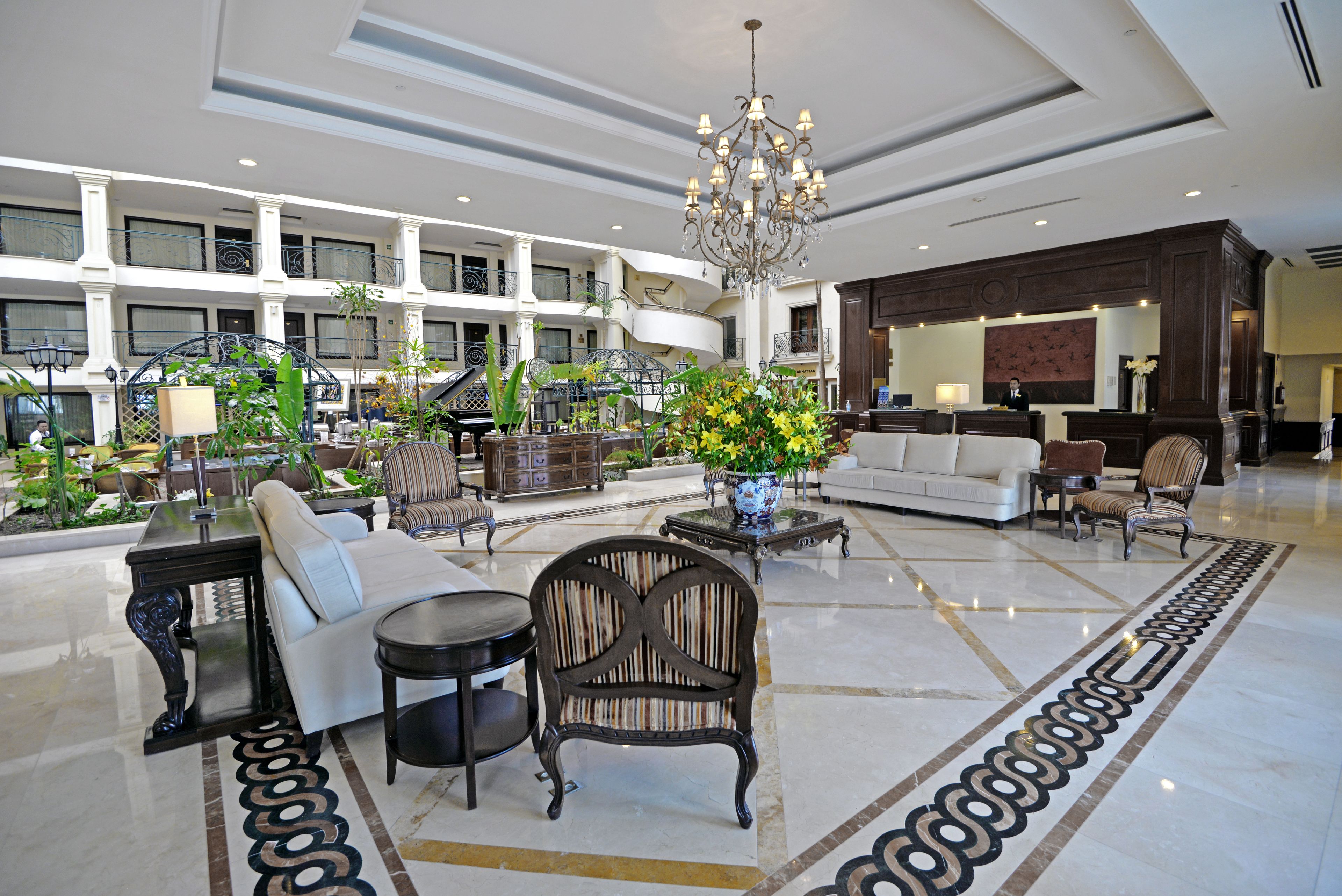 Eine großzügige Lobby mit einer zentralen Sitzecke, einem Empfangstresen und einem Chandelier.