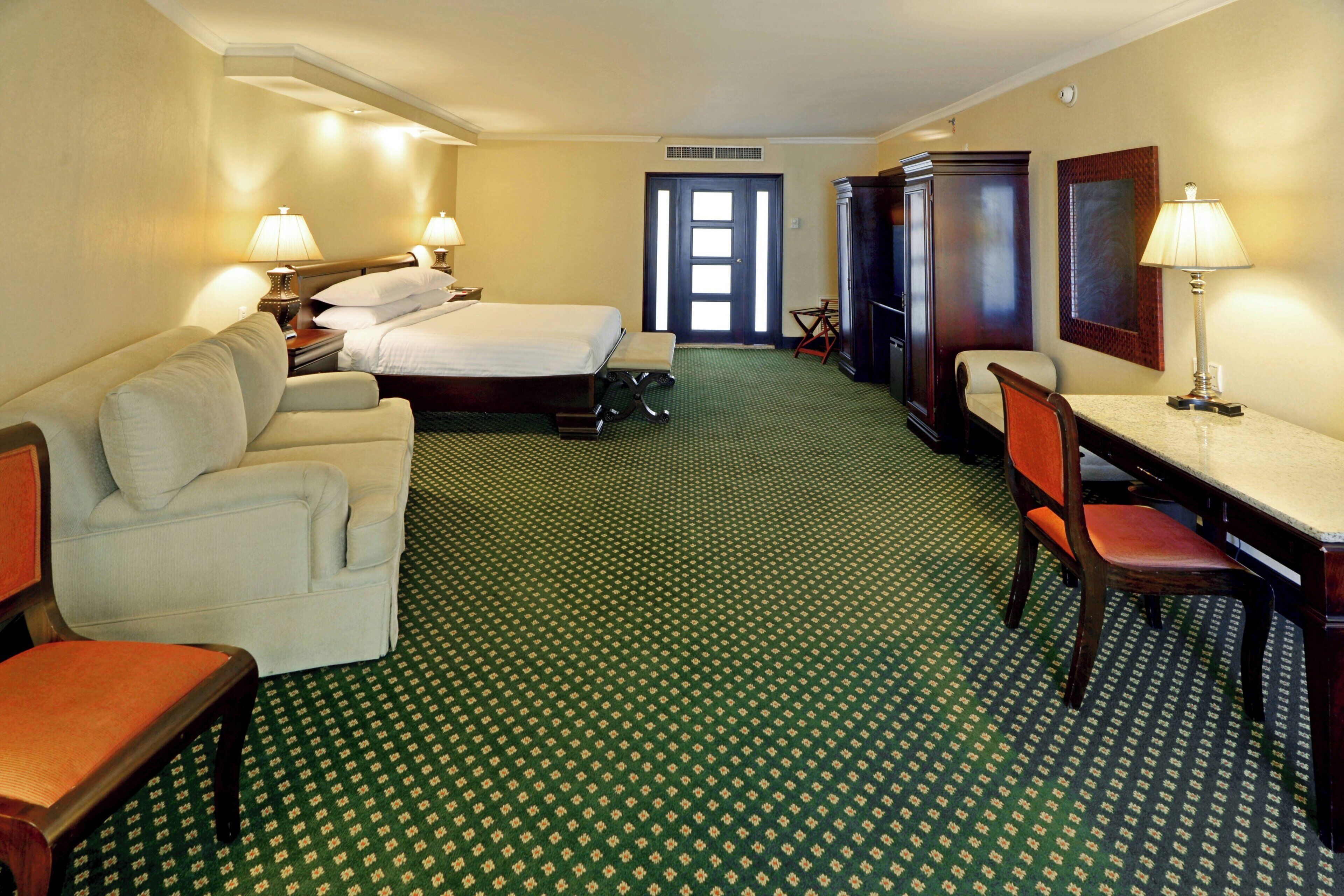 Une chambre d’hôtel avec un lit, un canapé, un bureau et une chaise.