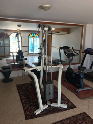 A gym with exercise equipment, a treadmill, and a stationary bike. - Ghani Palace Hotel (Salmiya)