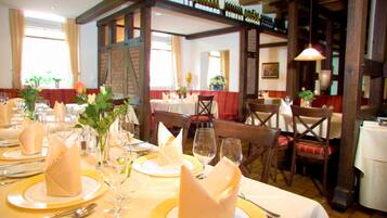 Ein Restaurant mit gedeckten Tischen, mit ordentlich gefalteten Servietten, Weingläsern und verschiedenen Tischgestaltungen.