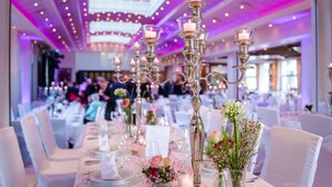 A banquet hall with tables set for a formal event, featuring candle holders and floral centerpieces. - Hotel Leugermann (Ibbenbueren)