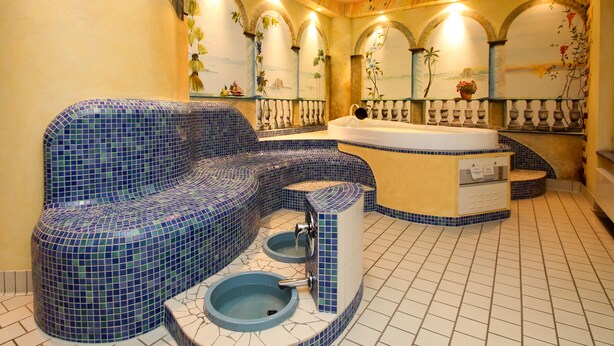 A bathroom with a blue mosaic tub, a separate shower area, and a small sink. - Hotel Leugermann (Ibbenbueren)