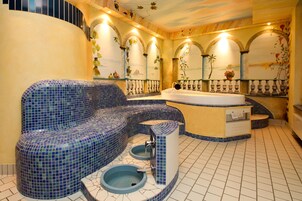 Un baño con una bañera de mosaico azul, zona de ducha independiente y un lavamanos pequeño.