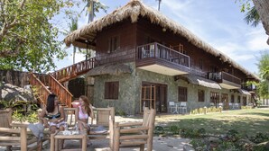 A two-story house with a thatched roof, a balcony, and a garden area with outdoor furniture. - The Ananyana Beach Resort by SMS Hospitality (Panglao)