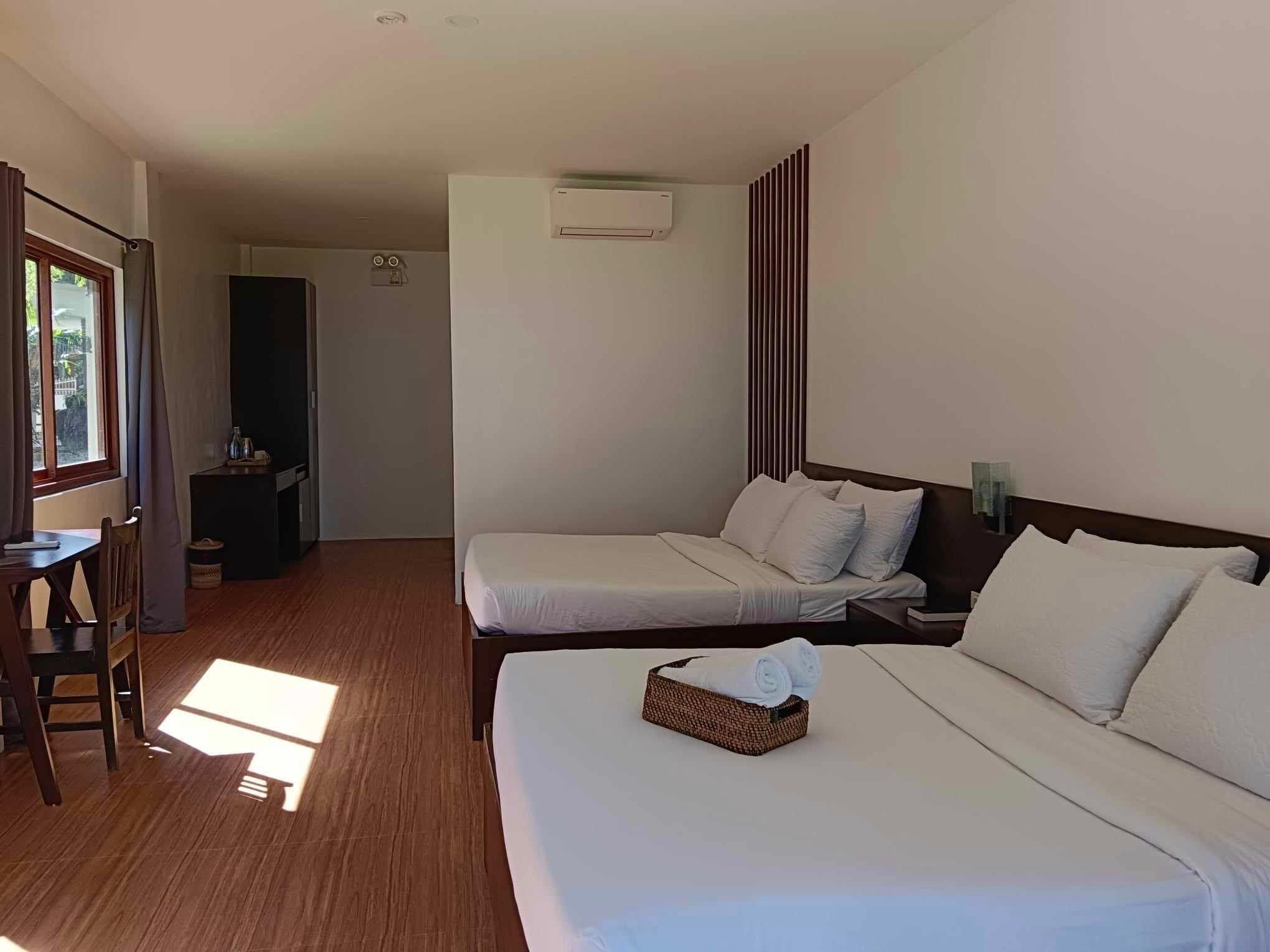 A hotel room with two beds, a desk, and a wardrobe.