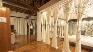 A room with a wooden floor, a bed with a canopy, and a large window with curtains. - The Ananyana Beach Resort by SMS Hospitality (Panglao)