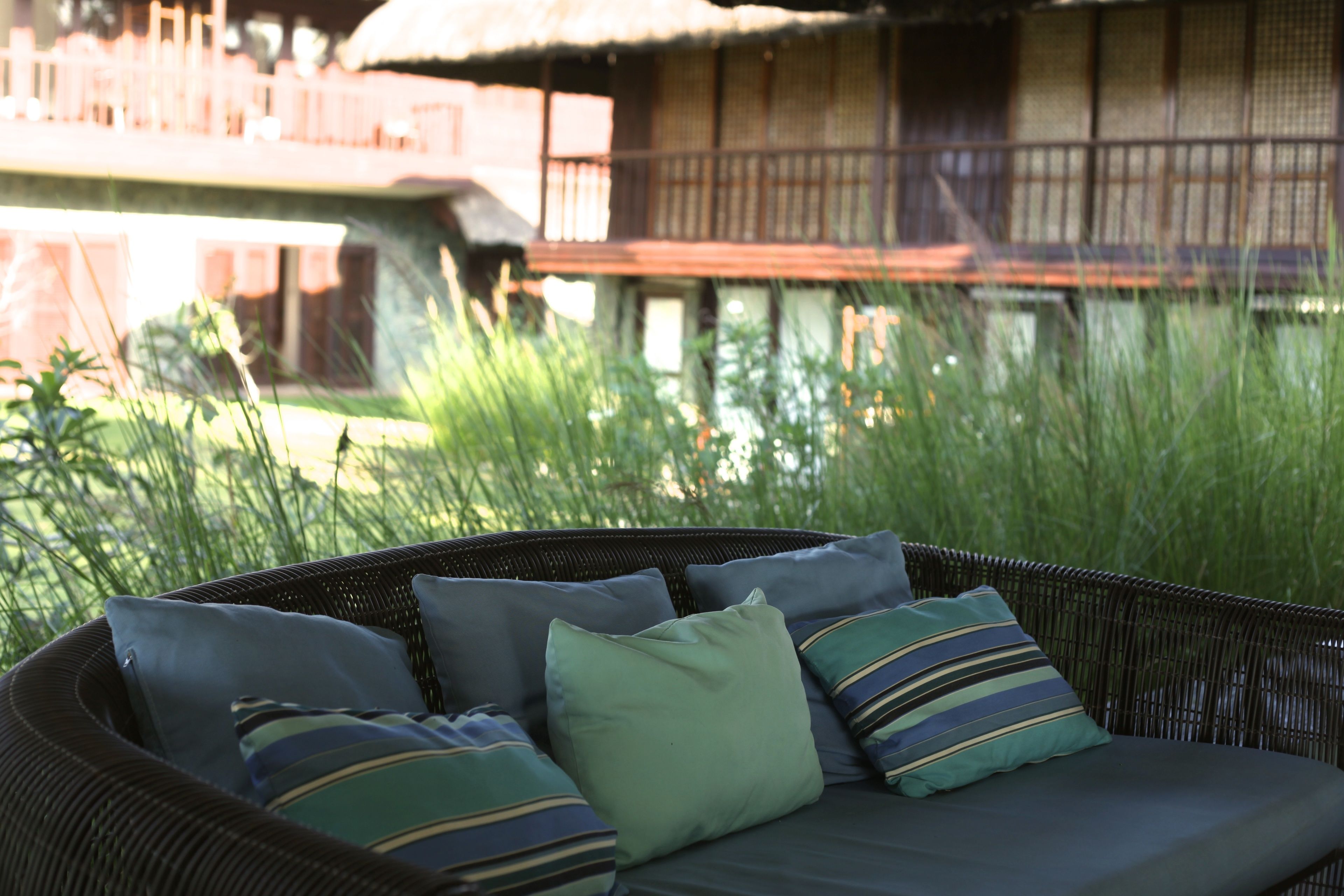 A wicker sofa with cushions in a garden area.
