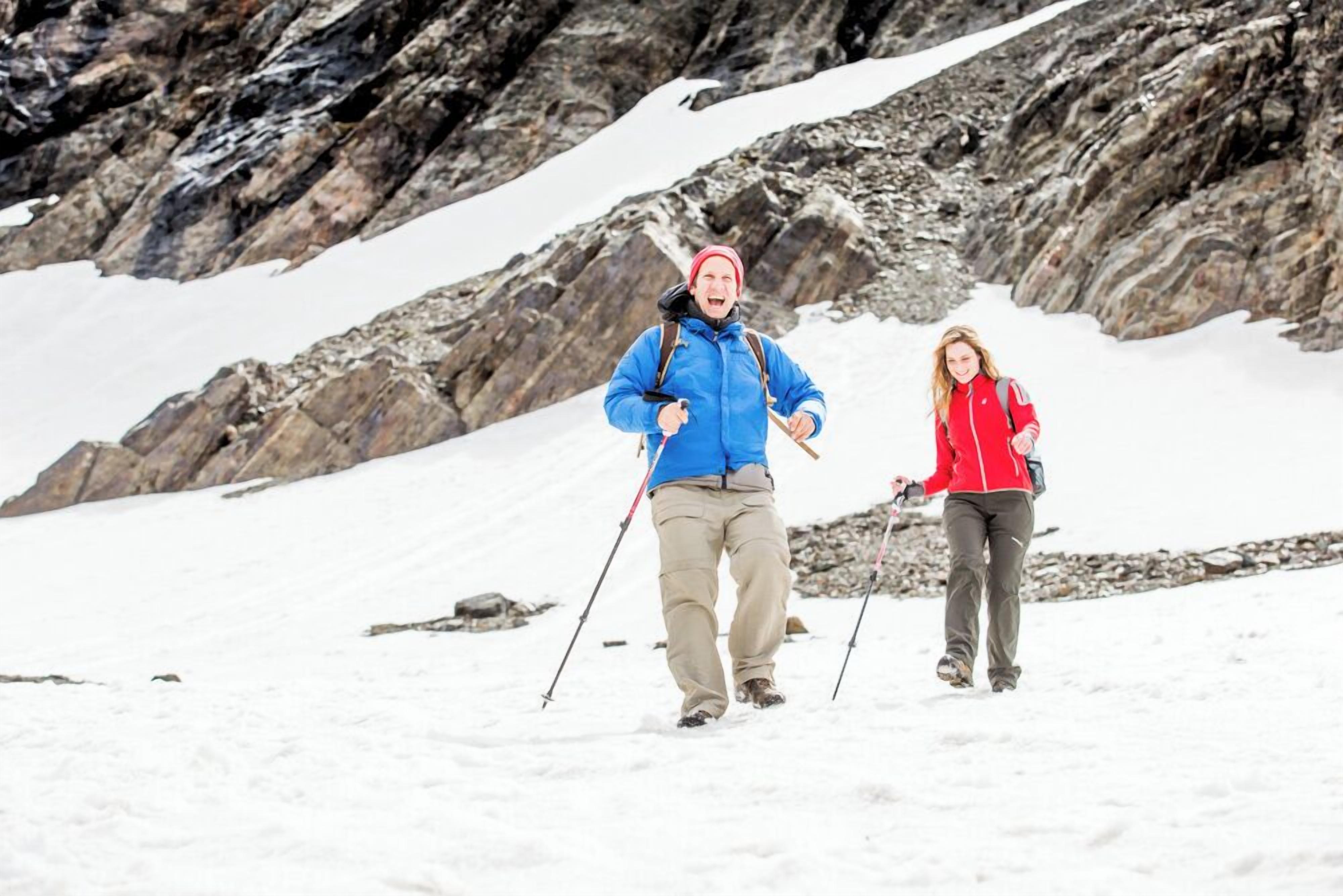 Two people hiking in a snowy mountainous area.