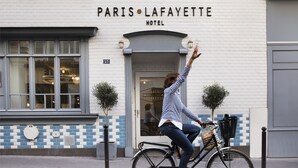 A woman on a bicycle in front of the Paris Lafayette Hotel. - Hotel Paris La Fayette (Paris)