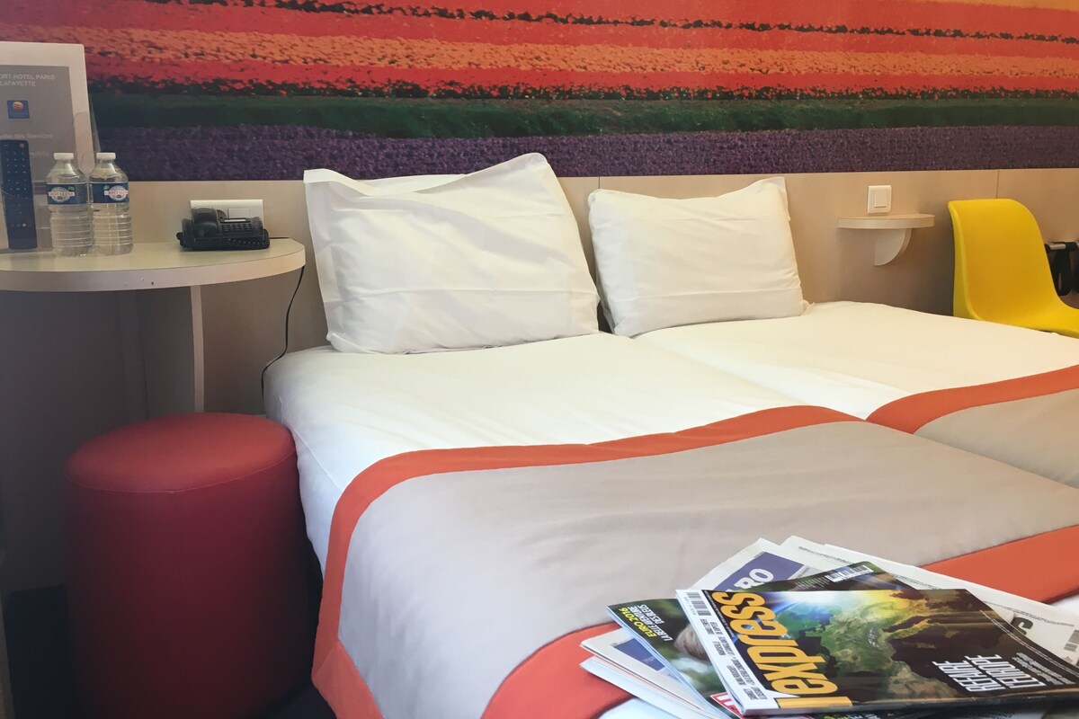 A hotel room with a bed, a desk with a phone, and a chair.