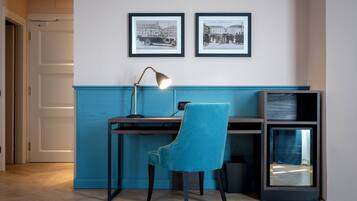 Ein Zimmer mit einem Schreibtisch, einem Stuhl und zwei gerahmten Fotografien an der Wand.