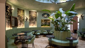 A restaurant with green seating, wooden floors, and tropical wall art. - Stadt Hotel Citta (Bolzano)